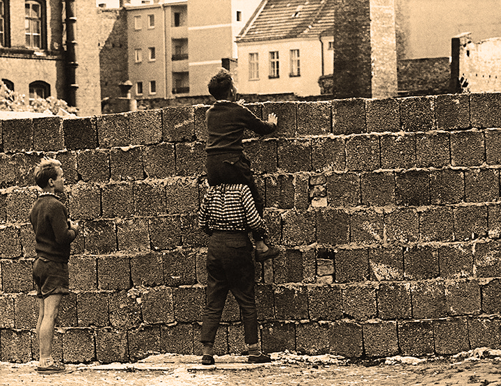 Three children look over the Berlin Wall dividing East (USSR) and West Berlin (democracy)